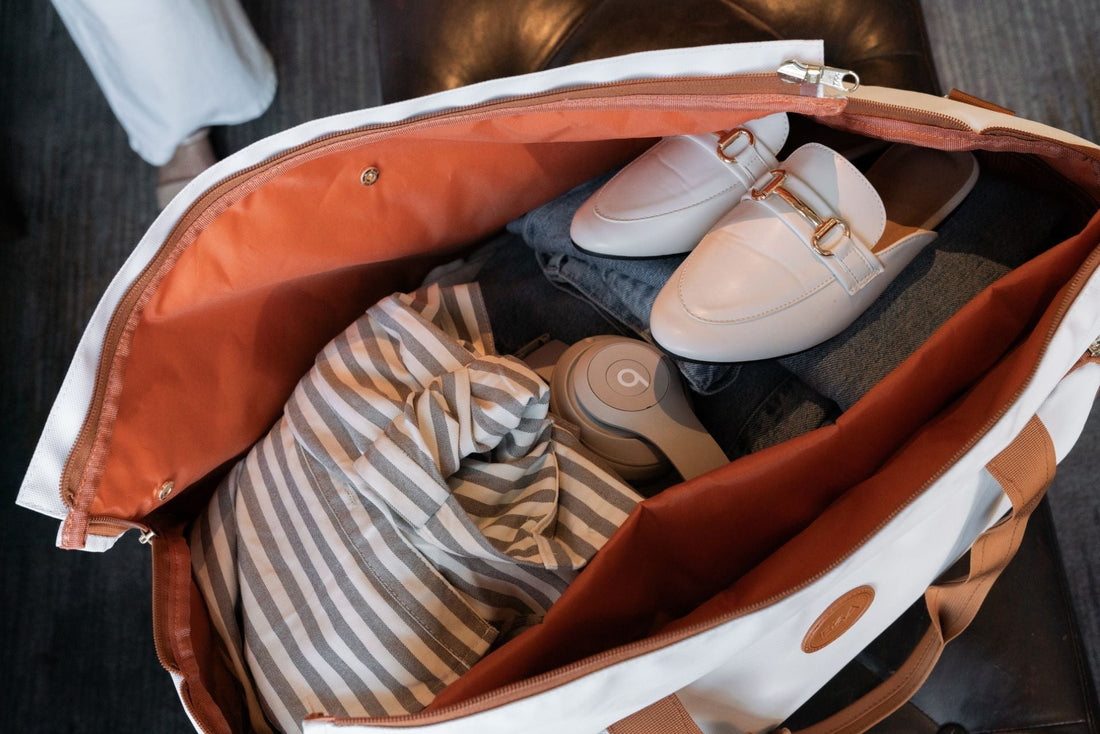 Interior of a convertible duffle bag packed with clothing, shoes, and headphones for travel.