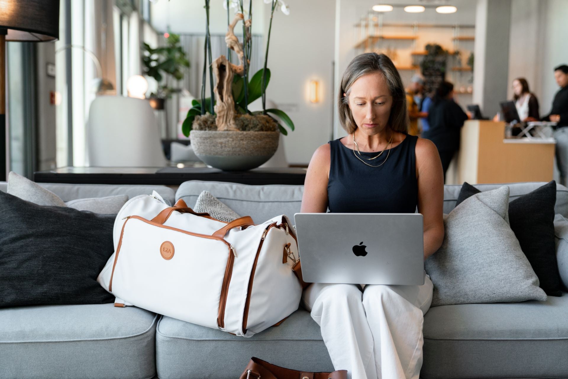 Woman working on a laptop next to a stylish Caribbean Convertible Duffle, perfect for travel and adventures.