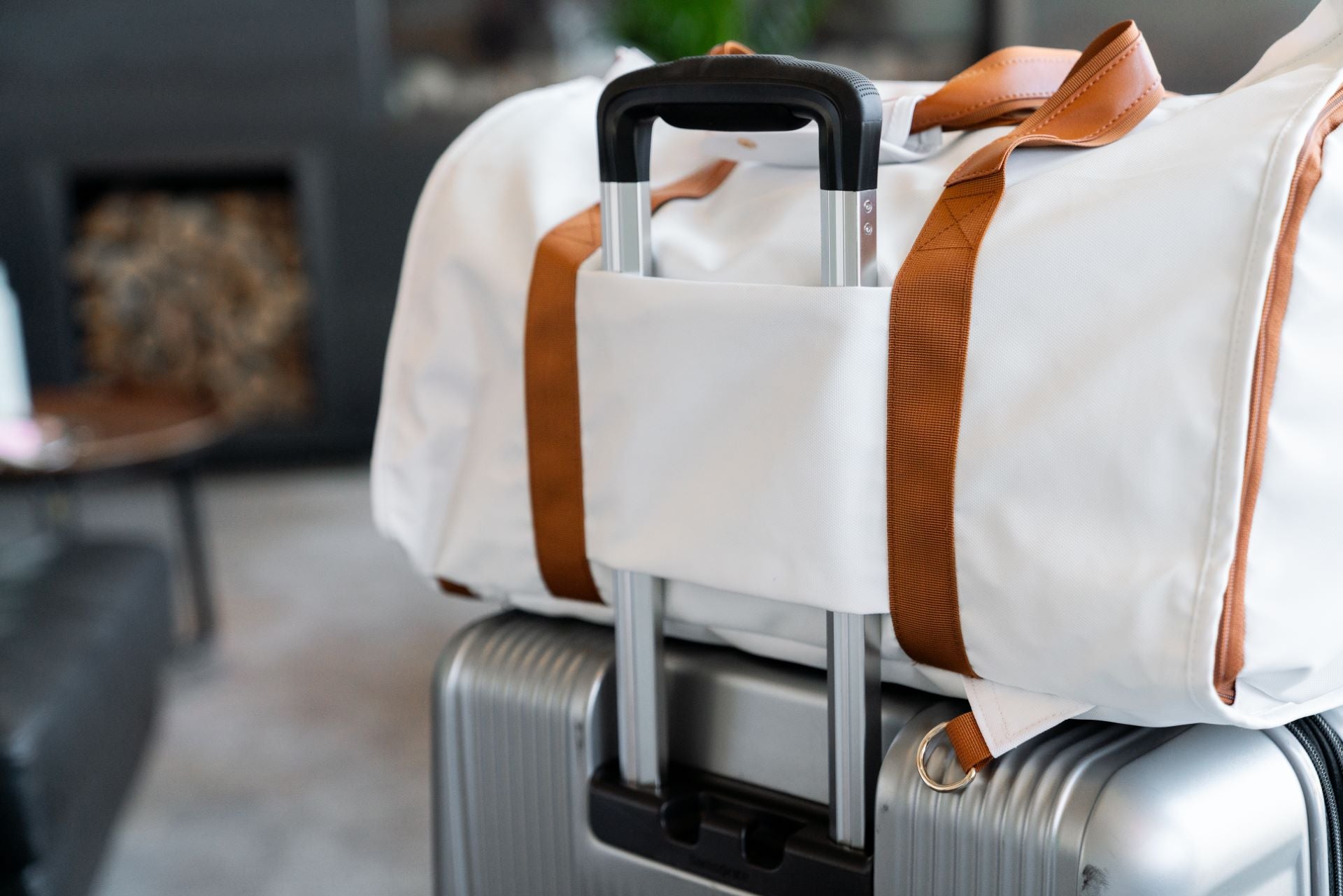 Convertible duffle bag securely resting on suitcase, featuring stylish leather straps and a sleek white design.