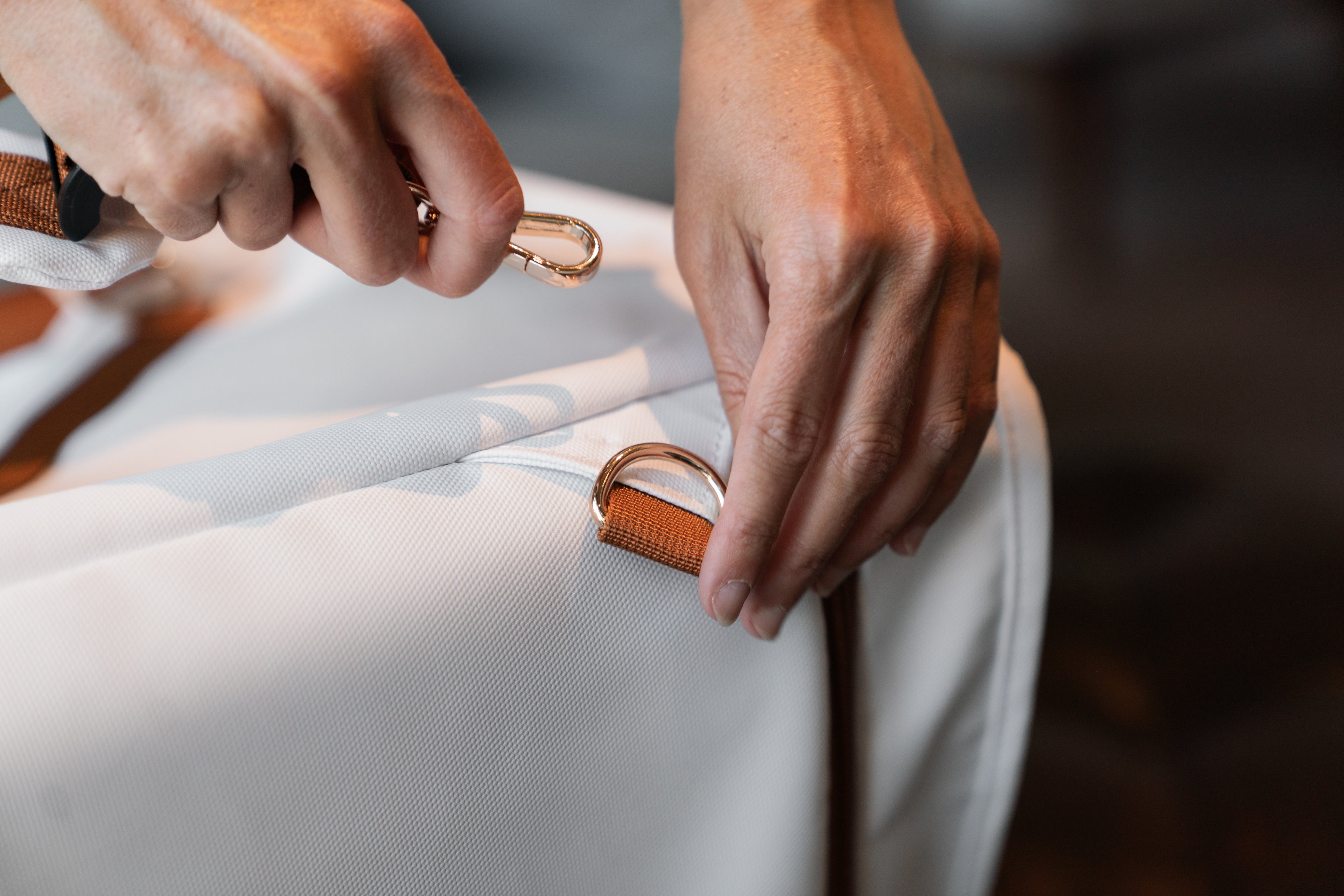 Close-up of hands adjusting a convertible duffle bag strap, showcasing its versatile design and high-quality materials.